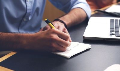 Wondering how to become a juvenile probation officer? Here, a person completes the juvenile probation requirements of taking notes during a meeting with a child.