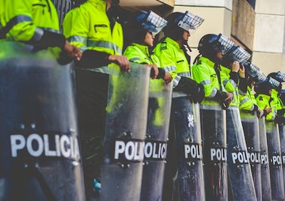A line of cops hold riot shields.