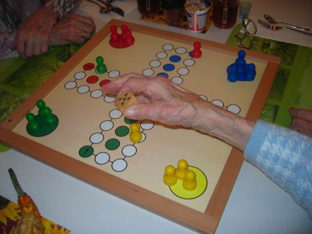recreation assistant leads seniors in a board game