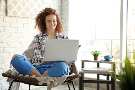young woman looking at her laptop while she takes online college classes