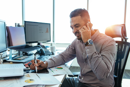 Male accountant taking a phone call at his computer