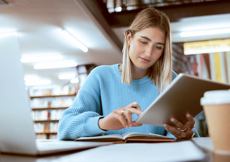 young woman working on her ipad while studying for her online college degree