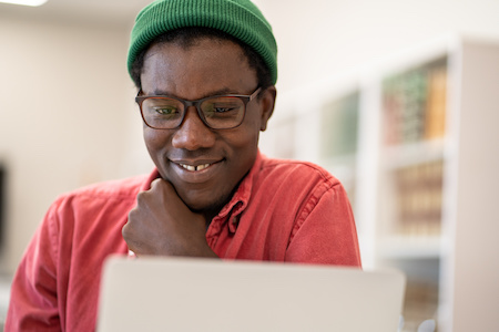 young man taking online classes looking at his laptop